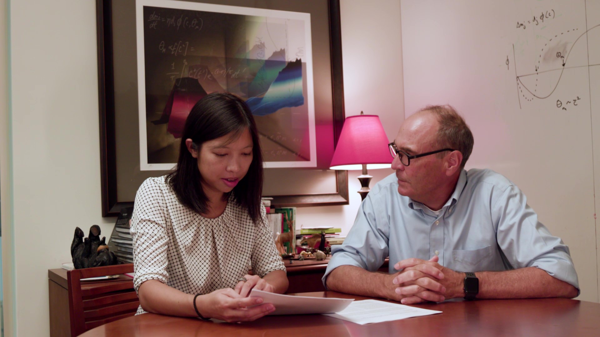 Ming-fai Fong sits at a wood table with Mark Bear in his office