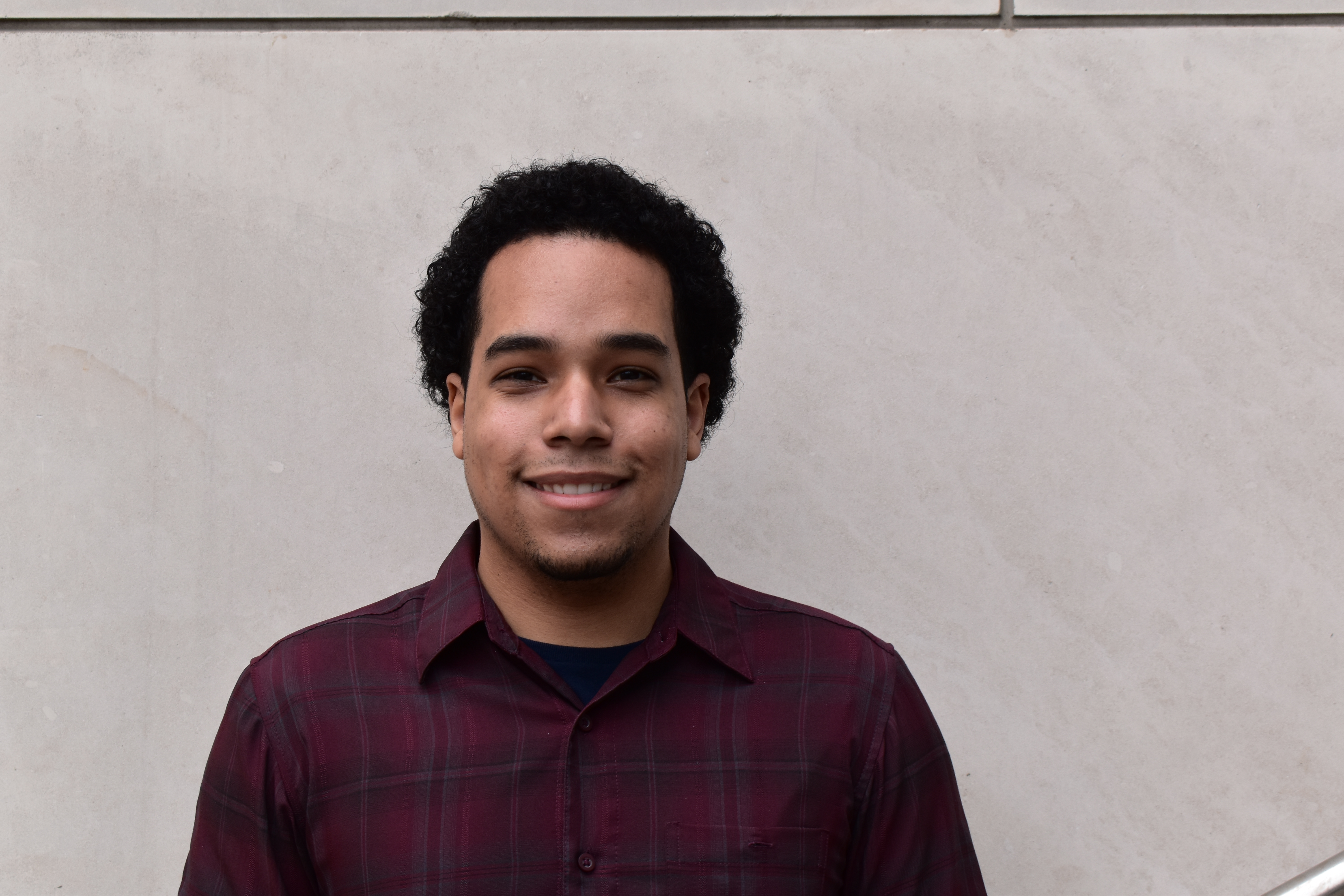 A young man stands infront of a light gray marble background