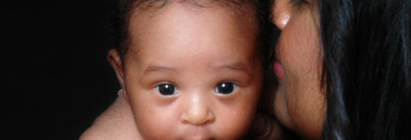 A baby looks over his mother's shoulder