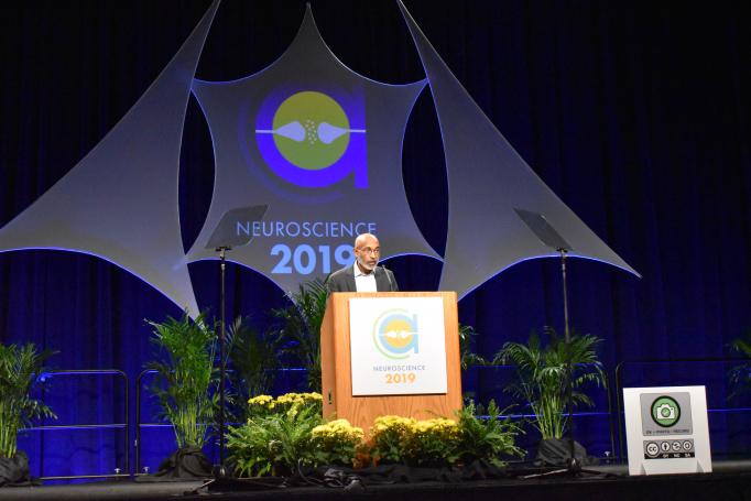 Emery Brown speaks at the SfN podium with flowers on the stage below